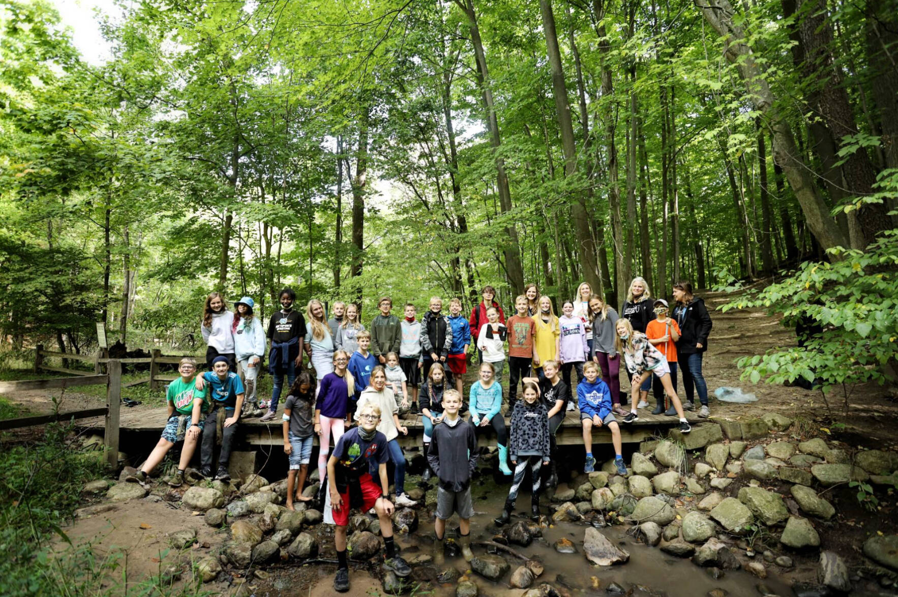 Students sitting for a group photo in the woods